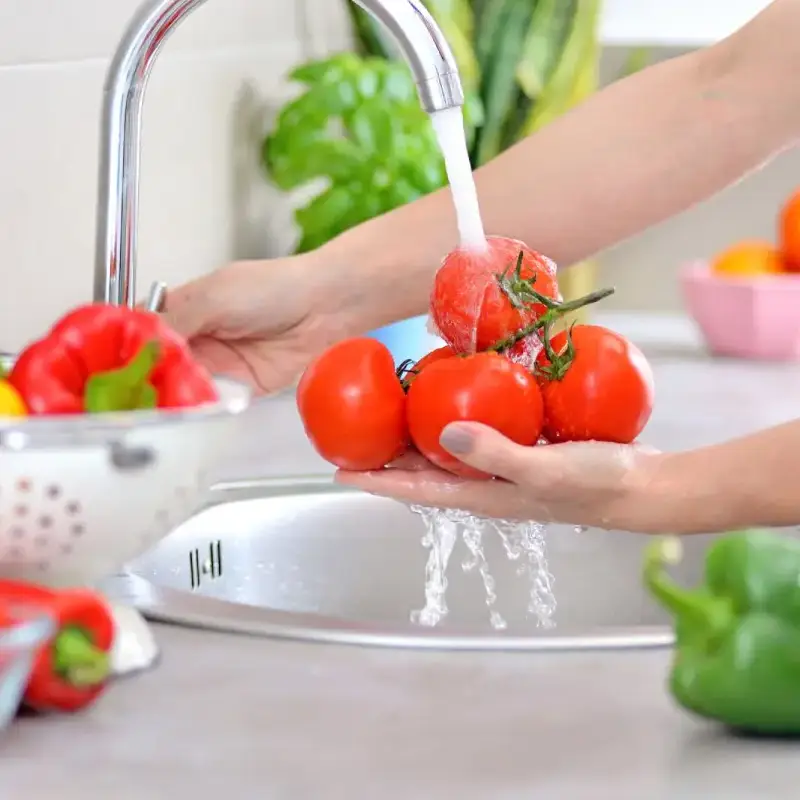 Washing fresh tomatoes under running water